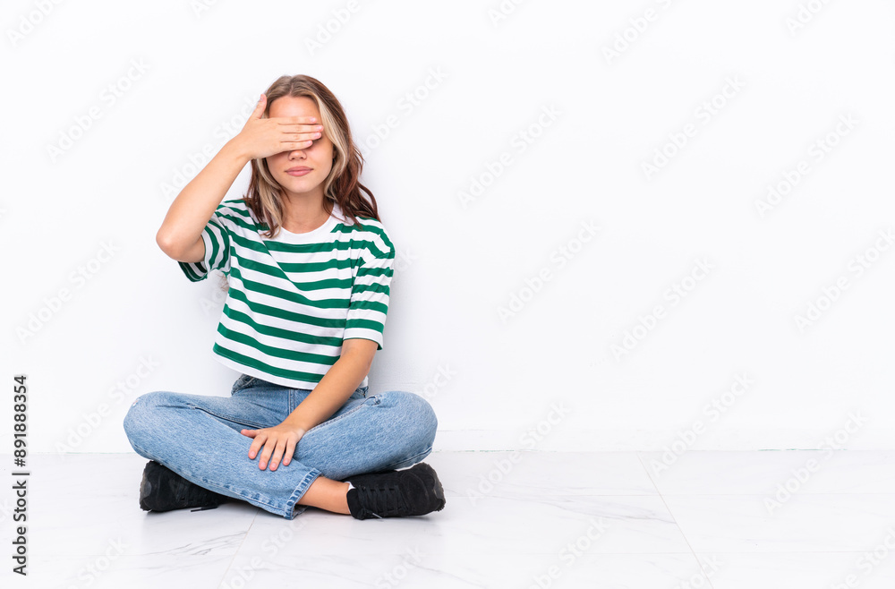 Young Russian girl sitting on the floor isolated on white background covering eyes by hands. Do not want to see something Young Russian girl sitting on the floor isolated on white background covering eyes by hands. Do not want to see something
