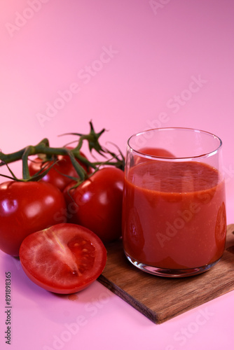 tomato juice with fresh tomatoes on a pink background. A fragrant drink.