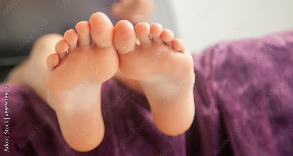 Close up beautiful young brunette girl reading on digital tablet, watching tv series on her application, sitting in living room. Selective focus on bare feet. Copy space. Close up beautiful young brunette girl reading on digital tablet, watching tv series on her application, sitting in living room. Selective focus on bare feet. Copy space.