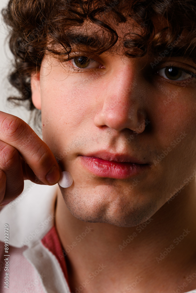 Fototapeta premium Young man uses acne stickers as bandage not to touch or squeeze pimple. Using acne pimple patch to clean the face from zits.