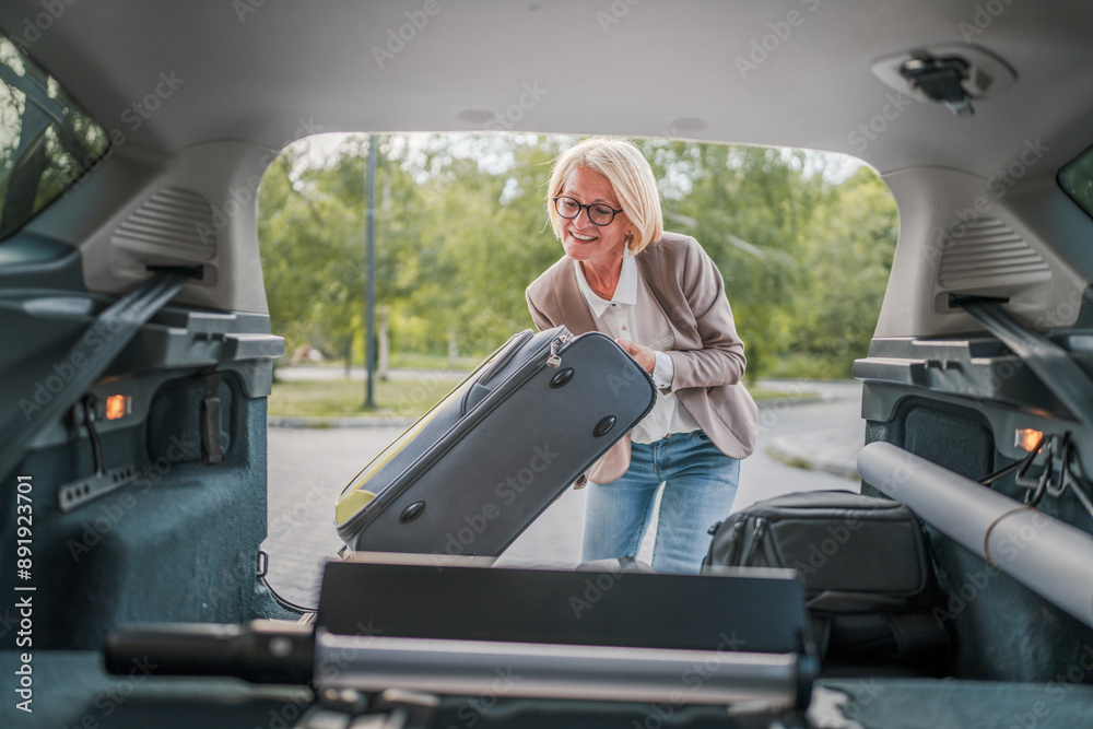 © Miljan Živković - mature blonde woman travel take stuff belongings from the back of car