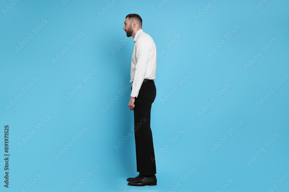 Man with poor posture on light blue background Man with poor posture on light blue background