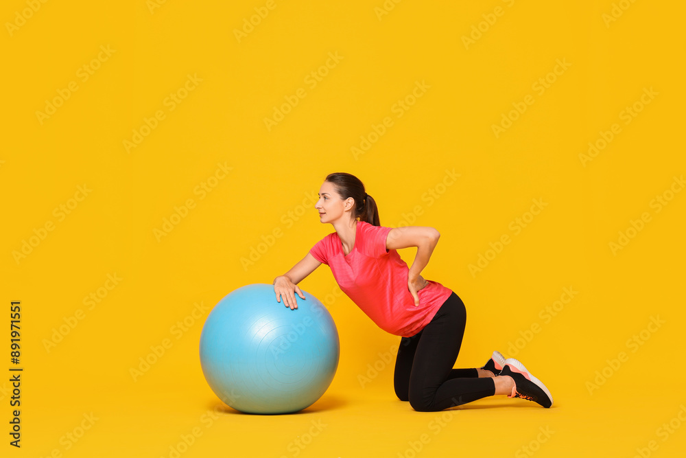 Beautiful pregnant woman doing exercises with fitball on yellow background Beautiful pregnant woman doing exercises with fitball on yellow background