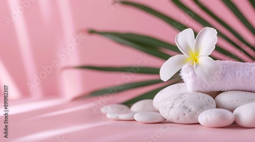 beach pebbles and towel with fragipani leaf on pink background