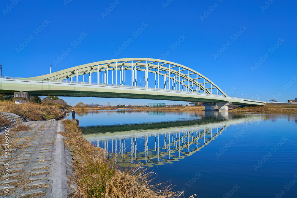 Obraz premium 川崎市多摩区の稲田多摩川公園付近から多摩川に水面反射する多摩水道橋を見る