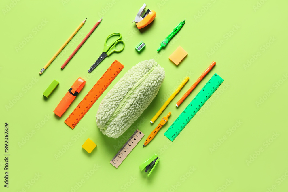 Naklejka premium Pencil case with different stationery on green background. Top view