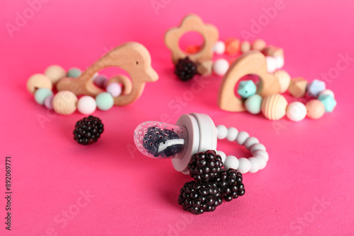 Baby nibbler with ripe blackberry and teethers on color background photo