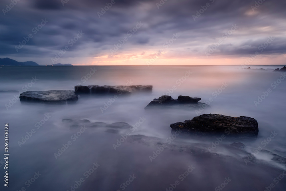 Sunset on Azkorri beach, Getxo, Bizkaia with waves breaking between the rocks in a long exposure Sunset on Azkorri beach, Getxo, Bizkaia with waves breaking between the rocks in a long exposure