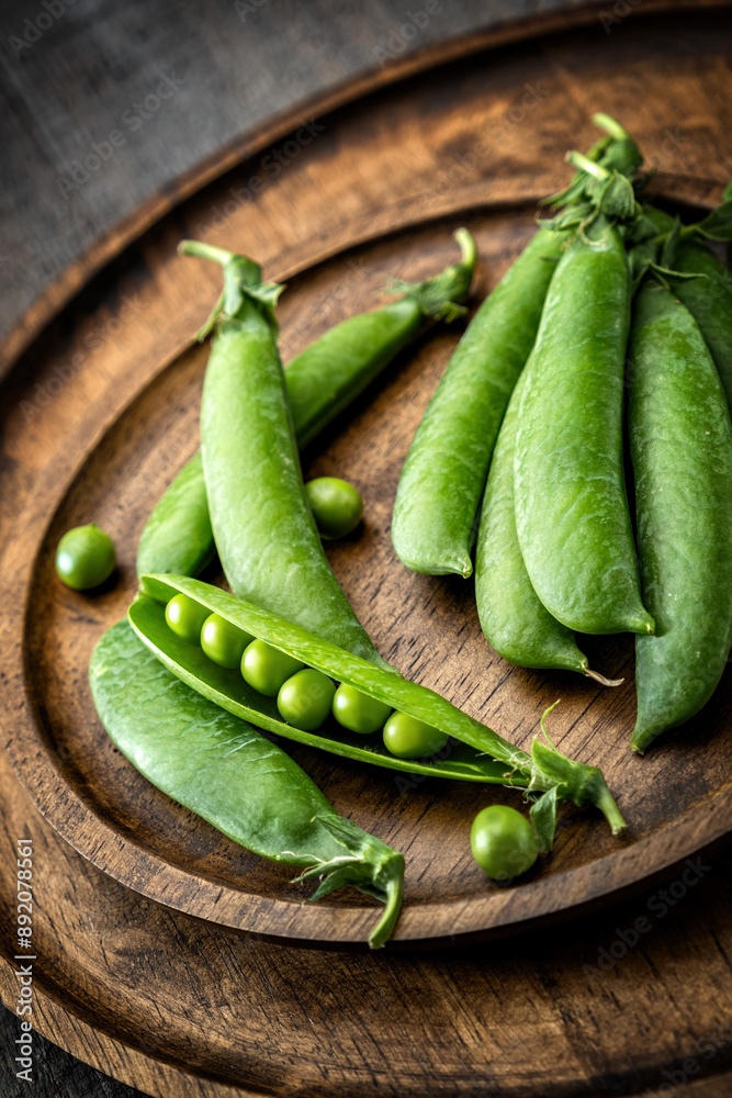 Green young sweet peas arranged beautifully on wooden plates, rustic, close-up. Green young sweet peas arranged beautifully on wooden plates, rustic, close-up.