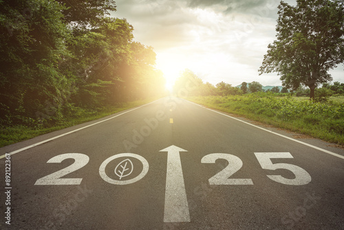 New year 2025 straightforward for environmental sustainability concept. Text 2025, save the world, leaf icon on the road in the middle of asphalt road at sunset. Ecological balance, sustainability.