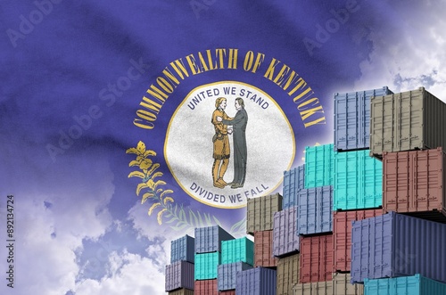 Kentucky US state flag and big stack of shipping cargo containers in docks with sky background close up