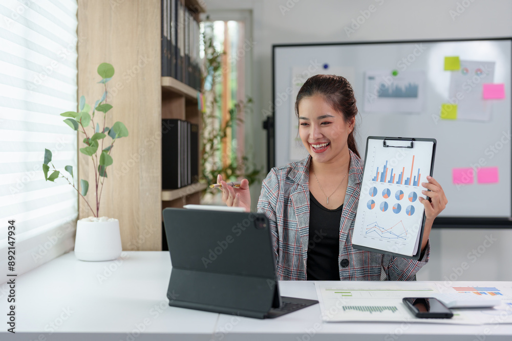 Asian businesswoman sitting in an office looking with graph detail on laptop computer Chart of real estate business growth data in the office. Asian businesswoman sitting in an office looking with graph detail on laptop computer Chart of real estate business growth data in the office.