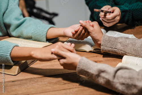 A group of people sits together, reading the Bible and praying. Their expressions reflect deep faith and friendship, creating a serene atmosphere filled with love, hope, and spiritual connection.