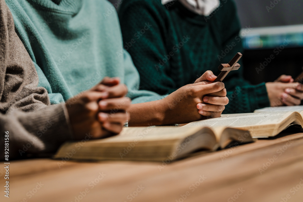Fototapeta premium A group of people sits together, reading the Bible and praying. Their expressions reflect deep faith and friendship, creating a serene atmosphere filled with love, hope, and spiritual connection.