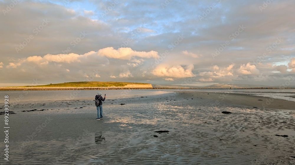 woman hiker backpacker enjoying coastal sunset scenery at sandy Silverstrand beach, Galway, Ireland, adventure and lifestyle concept, people in nature background
