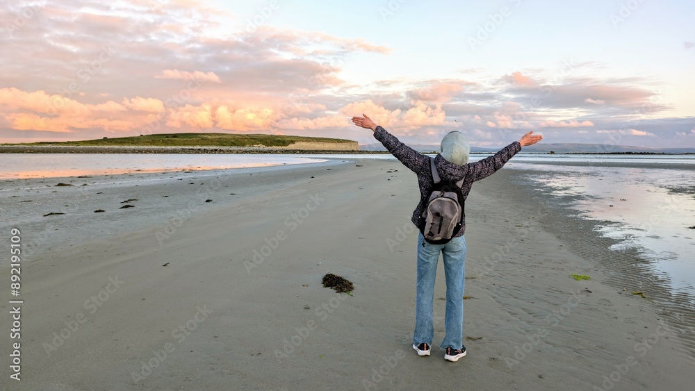 woman hiker backpacker enjoying coastal sunset scenery at sandy Silverstrand beach, Galway, Ireland, adventure and lifestyle concept, people in nature background