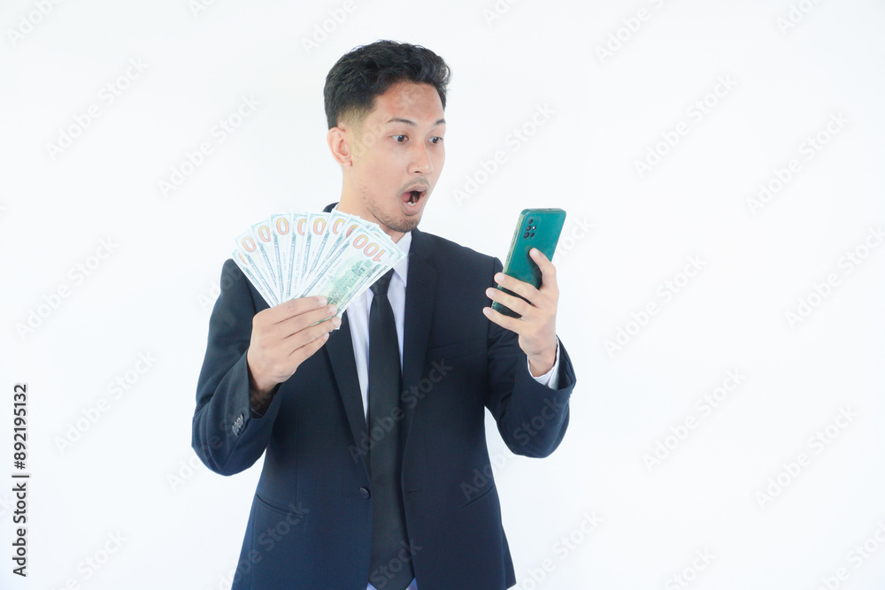 Online profit. Happy young man holding smartphone and dollar cash, enjoying financial success, recommending new mobile app, standing on white background Online profit. Happy young man holding smartphone and dollar cash, enjoying financial success, recommending new mobile app, standing on white background