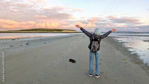 Obraz na płótnie woman hiker backpacker enjoying coastal sunset scenery at sandy Silverstrand beach, Galway, Ireland, adventure and lifestyle concept, people in nature background w salonie