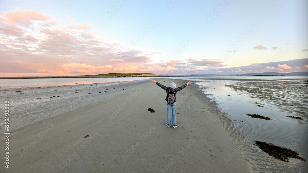 woman hiker backpacker enjoying coastal sunset scenery at sandy Silverstrand beach, Galway, Ireland, adventure and lifestyle concept, people in nature background
