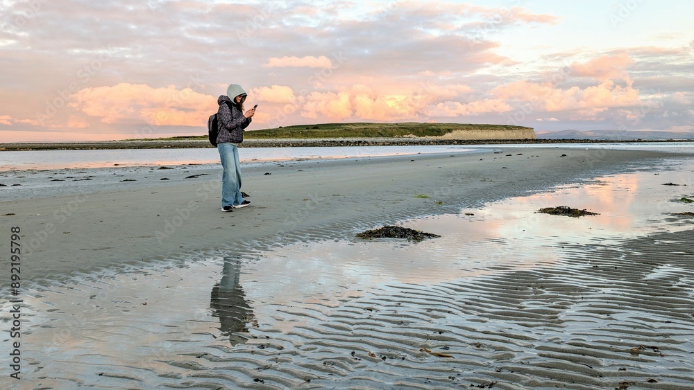 woman hiker backpacker enjoying coastal sunset scenery at sandy Silverstrand beach, Galway, Ireland, adventure and lifestyle concept, people in nature background