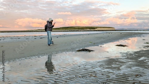 Obraz na płótnie woman hiker backpacker enjoying coastal sunset scenery at sandy Silverstrand beach, Galway, Ireland, adventure and lifestyle concept, people in nature background w salonie