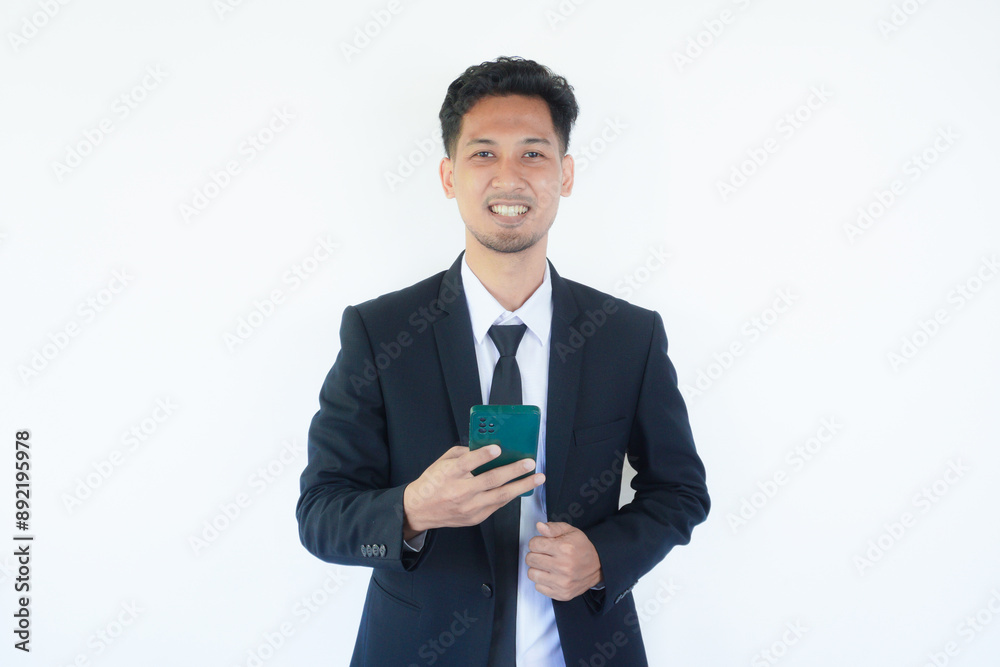Adult Asian man wearing black suit and tie smiling while using mobile phone Adult Asian man wearing black suit and tie smiling while using mobile phone
