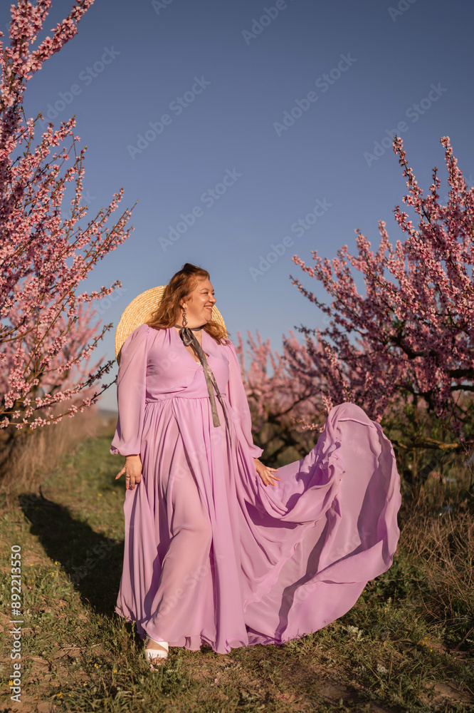 Woman blooming peach orchard. Against the backdrop of a picturesque peach orchard, a woman in a long pink dress and hat enjoys a peaceful walk in the park, surrounded by the beauty of nature. Woman blooming peach orchard. Against the backdrop of a picturesque peach orchard, a woman in a long pink dress and hat enjoys a peaceful walk in the park, surrounded by the beauty of nature.