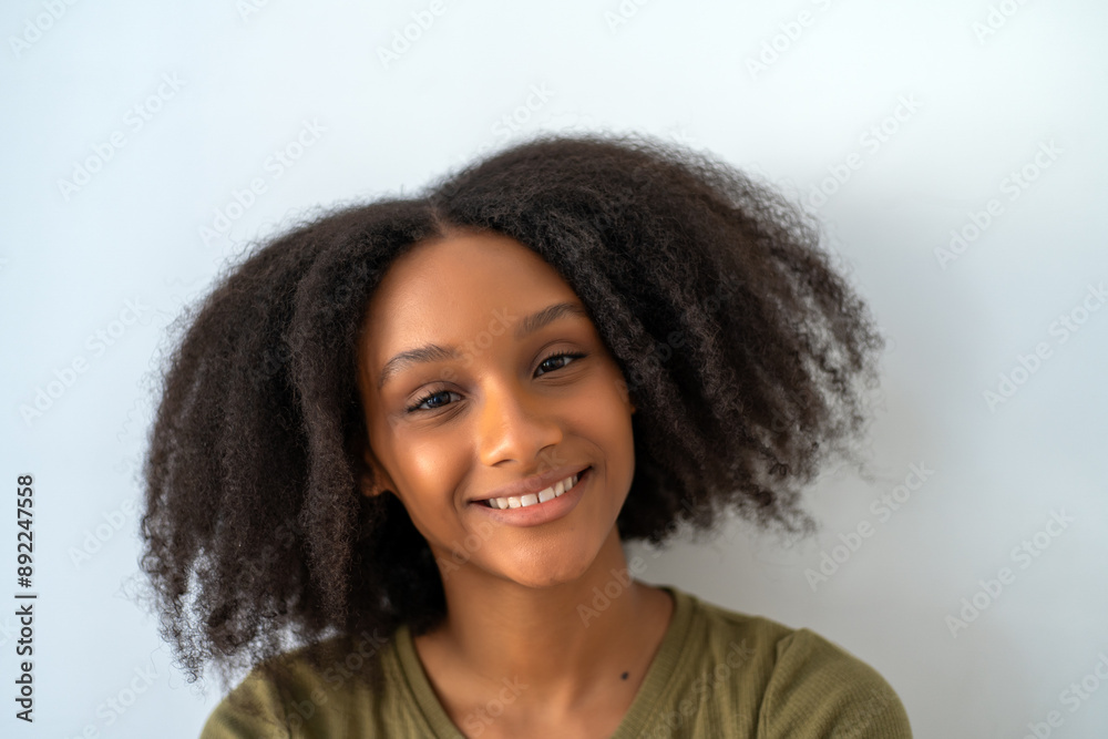 Portrait of smiling young African American woman with natural curly hair against plain background. Portrait of smiling young African American woman with natural curly hair against plain background.