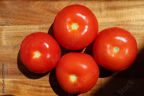 top down shot of four arranged tomatoes on wooden surface