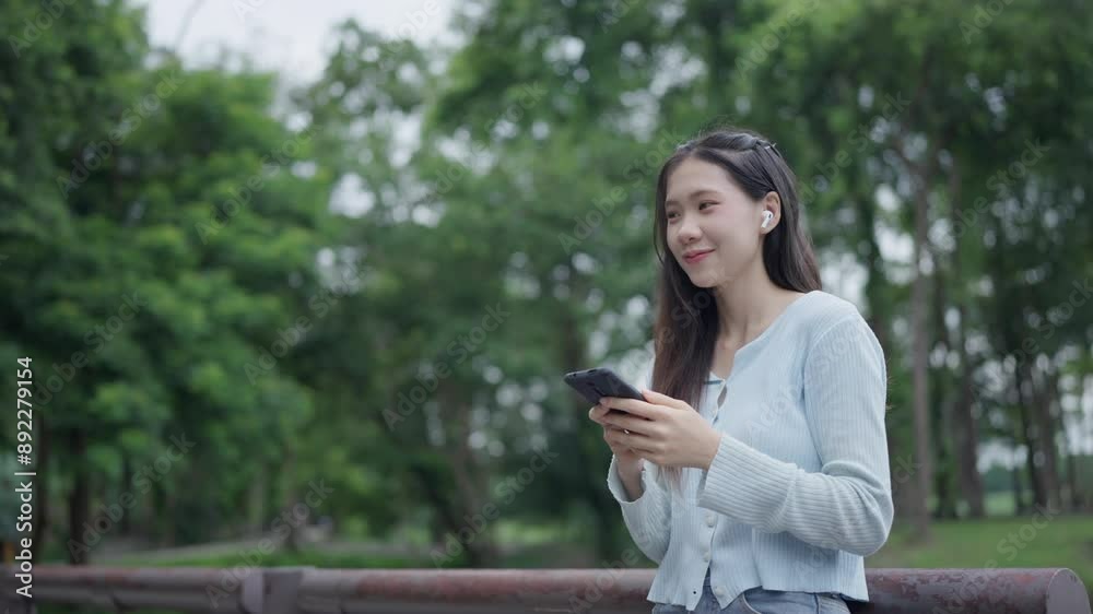 Asian woman using smartphone in park in sunny day Asian woman using smartphone in park in sunny day