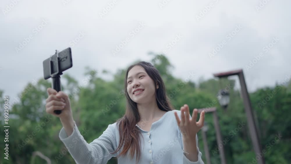 Asian woman using smartphone in park in sunny day for Vlog travel Asian woman using smartphone in park in sunny day for Vlog travel