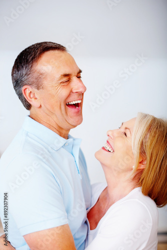 Senior couple, happy and laughing in house for love, hug or anniversary as romantic partner. Mature, people and affection for bonding, relationship and together in home with embrace, loyalty or care