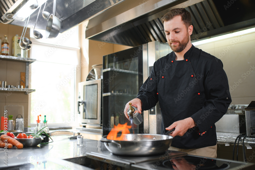 chef standing in restaurant and making flambe on frying pan chef standing in restaurant and making flambe on frying pan