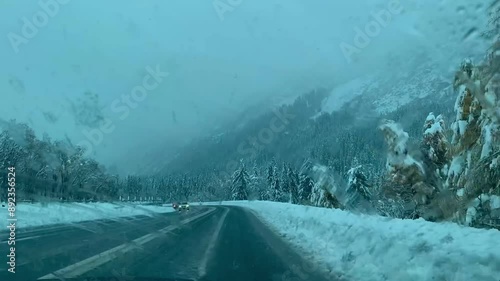 Video of a winter road surrounded by snowy mountains and dense forest. Captured from a car’s dashboard, showcasing the scenic snowy landscape and winding roads.
