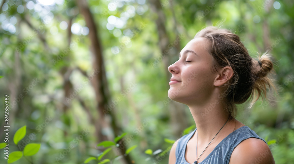 Young woman is practicing deep breathing, meditation or gratefulness or enjoying nature in a forest or woods Young woman is practicing deep breathing, meditation or gratefulness or enjoying nature in a forest or woods