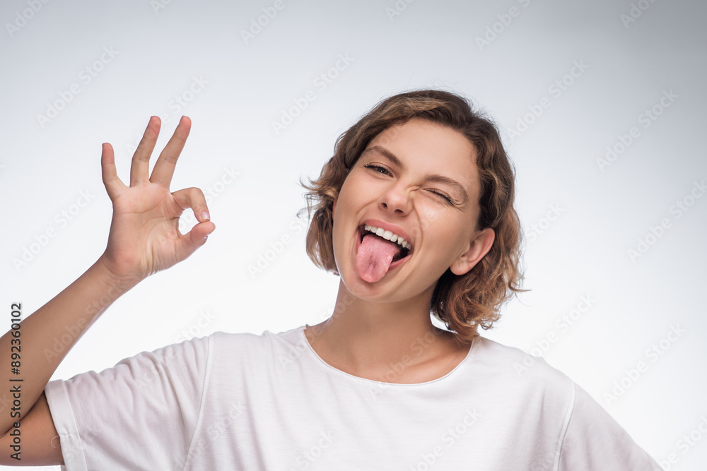 Cheerful Woman Winking and Making OK Sign with Tongue Out Cheerful Woman Winking and Making OK Sign with Tongue Out