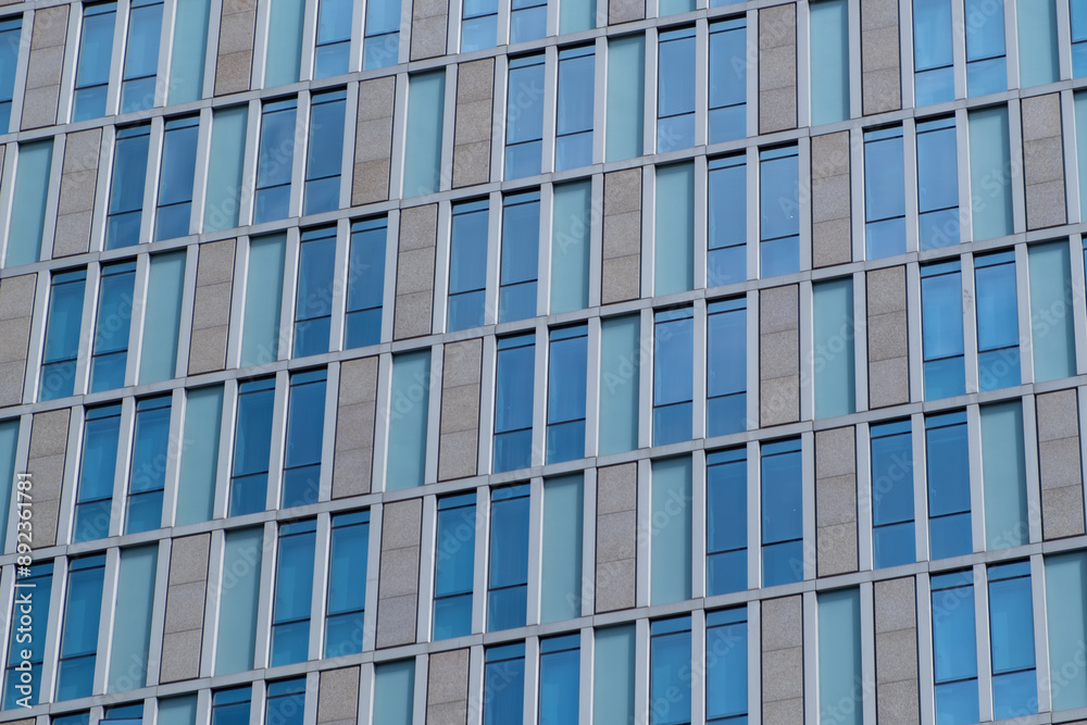 A detailed view of a building facade featuring a repetitive pattern of windows and panels. A detailed view of a building facade featuring a repetitive pattern of windows and panels.