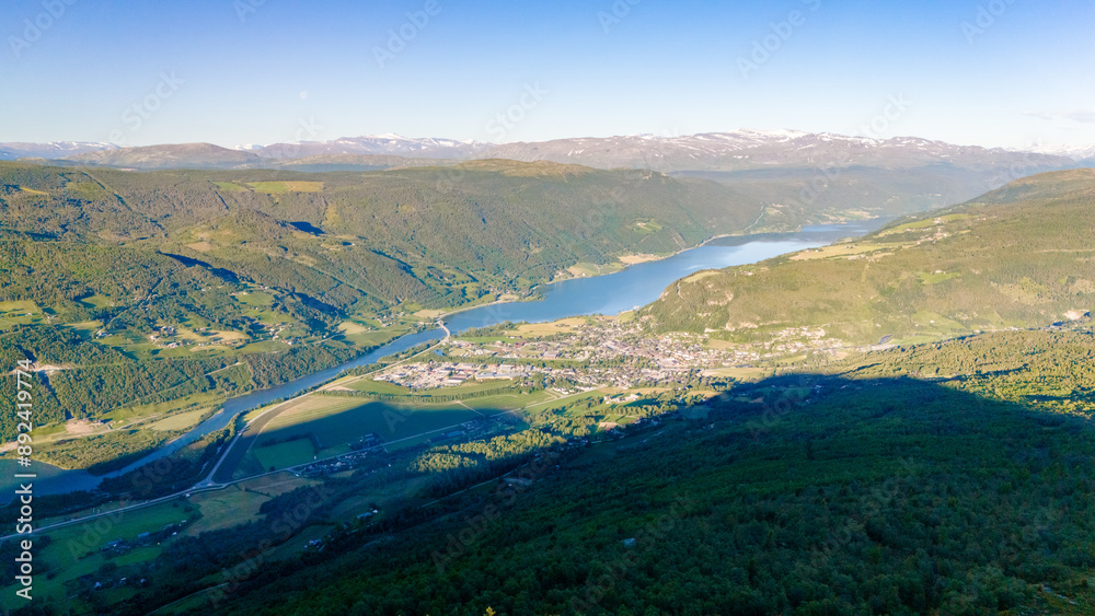A panoramic view of a Norwegian fjord, with snow-capped mountains in the distance, a winding river, and a small town nestled in the valley. Grimsdalen Norway A panoramic view of a Norwegian fjord, with snow-capped mountains in the distance, a winding river, and a small town nestled in the valley. Grimsdalen Norway