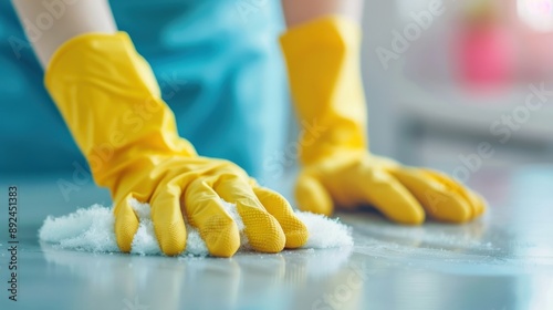 A person wearing yellow gloves is cleaning a table