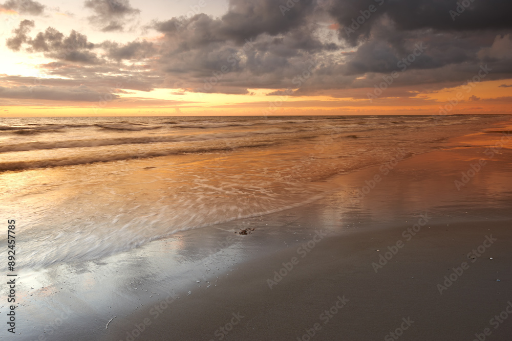 Sunset, beach and ocean for vacation, clouds and travel to Denmark for summer holiday adventure. Sea, location and sand on coast with sky, nature or horizon with waves on landscape outdoor in Jutland Sunset, beach and ocean for vacation, clouds and travel to Denmark for summer holiday adventure. Sea, location and sand on coast with sky, nature or horizon with waves on landscape outdoor in Jutland