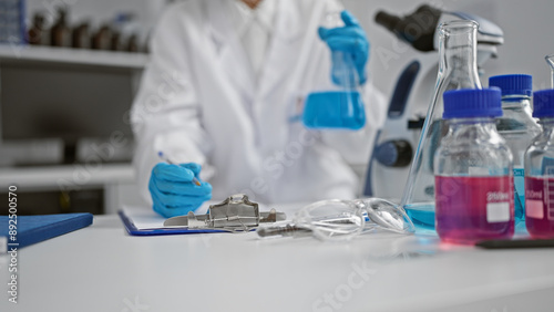 A focused caucasian woman scientist in a lab conducts an experiment with blue liquid, embodying professionalism and concentration.