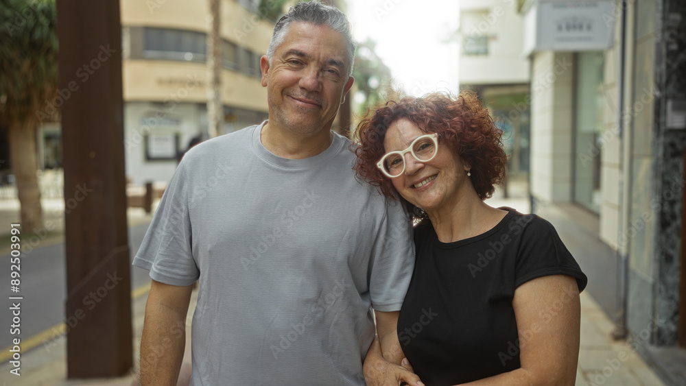Middle-aged couple standing together on an urban street, both smiling and embracing, reflecting a strong bond of love and happiness Middle-aged couple standing together on an urban street, both smiling and embracing, reflecting a strong bond of love and happiness