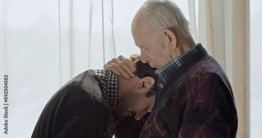 Anxious man waiting at a window staring out turning as he becomes aware of an old man behind them and then moving into an embrace of comfort. Anxious man waiting at a window staring out turning as he becomes aware of an old man behind them and then moving into an embrace of comfort.