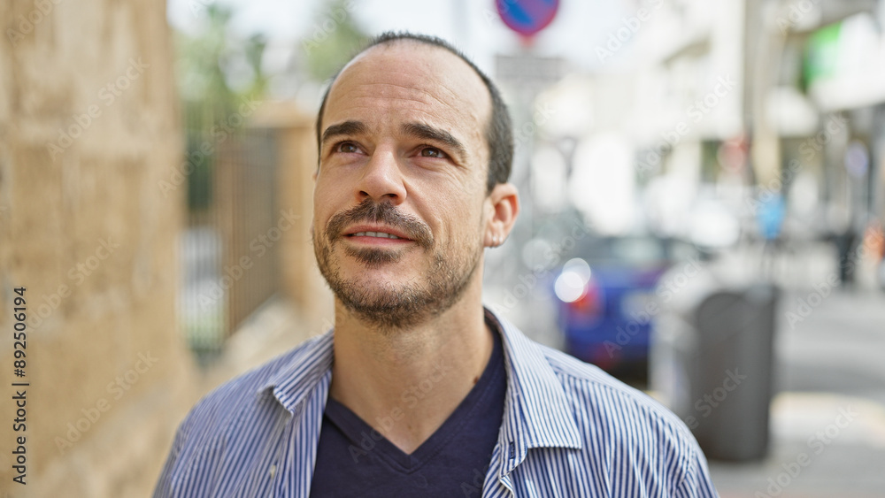 Hispanic bald man with beard in urban city street setting, exemplifying outdoor lifestyle. Hispanic bald man with beard in urban city street setting, exemplifying outdoor lifestyle.