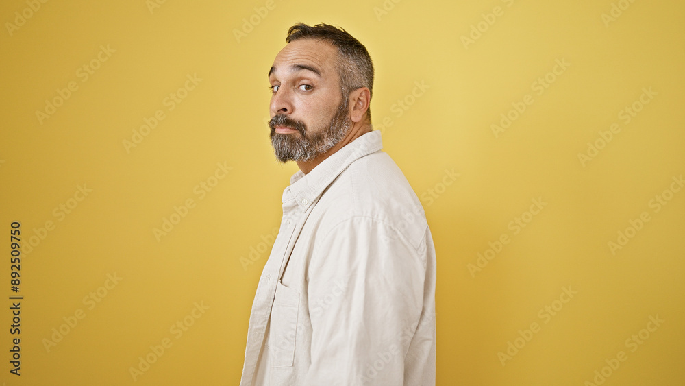 Mature hispanic man with grey beard posing against a vibrant yellow background, evoking a dignified yet approachable aura. Mature hispanic man with grey beard posing against a vibrant yellow background, evoking a dignified yet approachable aura.