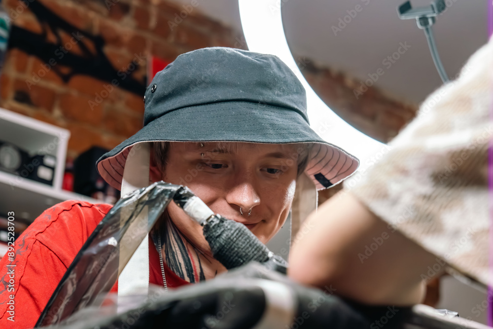 Tattoo master is tattooing a man's hand. Tattoo machine, safety and hygiene at work. Close-up of tattoo artist work. Tattoo salon Tattoo master is tattooing a man's hand. Tattoo machine, safety and hygiene at work. Close-up of tattoo artist work. Tattoo salon