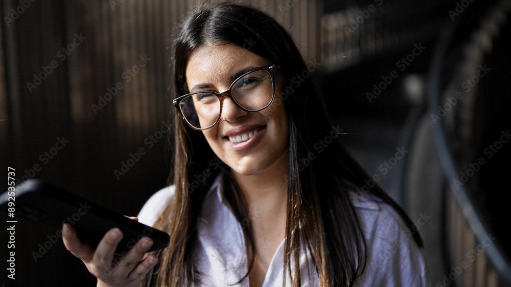 Young beautiful hispanic woman smiling happy using smartphone at the office Young beautiful hispanic woman smiling happy using smartphone at the office