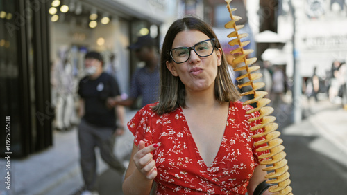 фотографія Beautiful hispanic woman joyfully eating crunchy, delicious chips on a stick at