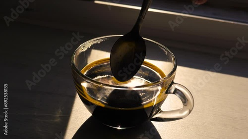 Mix aromatic brewed instant coffee with a spoon in a transparent cup, in slow motion, a drop of coffee falls into the cup. Close-up.