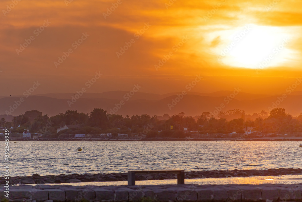 The sun is setting over the ocean, casting a warm glow over the water The sun is setting over the ocean, casting a warm glow over the water